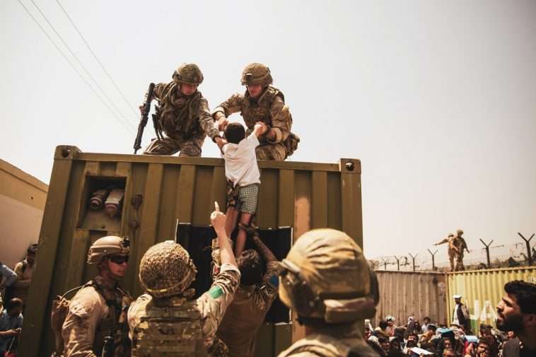Britiske og tyrkiske koalitionsstyrker samt amerikanske marinesoldater hjælper et barn under en evakuering i Hamid Karzai International Airport, Kabul, Afghanistan, 20. august. Foto af Staff Sgt. Victor Mancilla